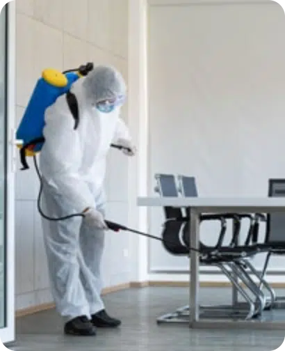 Person in full PPE disinfecting a conference room