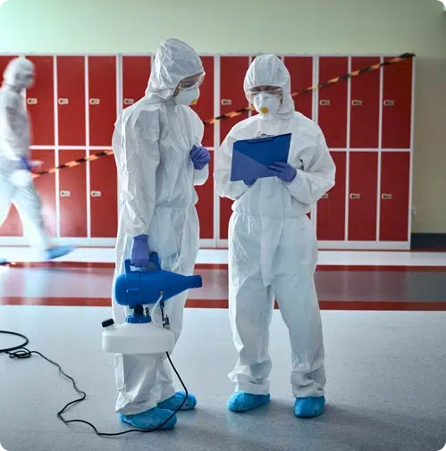 People in full PPE reviewing paperwork while cleaning a facility