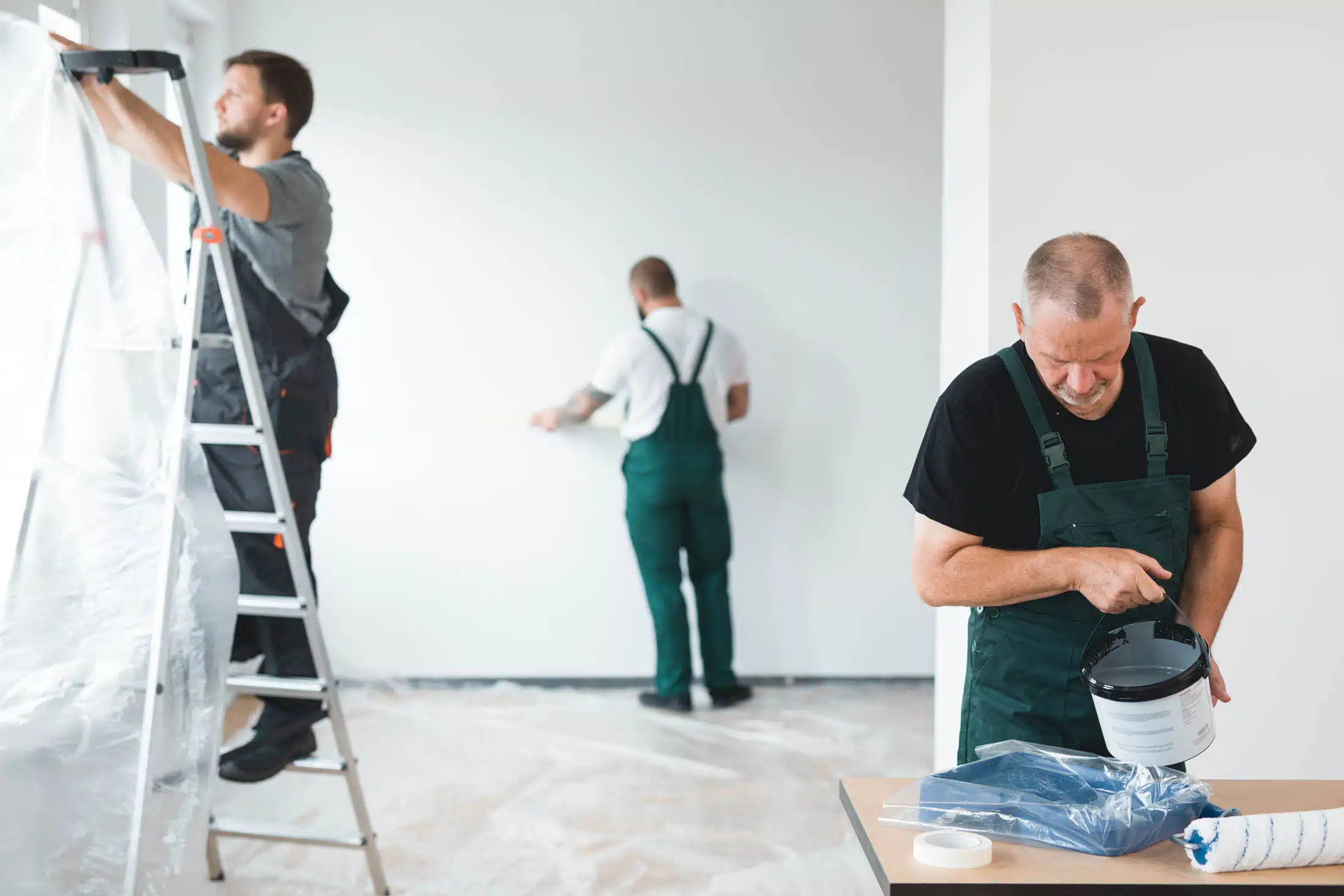 Three workers painting a room in a residential property
