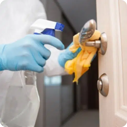Hands in PPE cleaning a door handle
