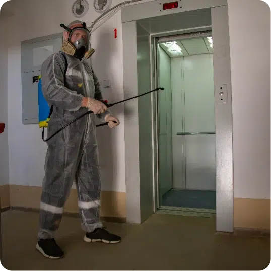 Person in full body PPE spraying disinfectant in a facility