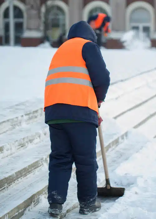 worker shoveling snow off of steps