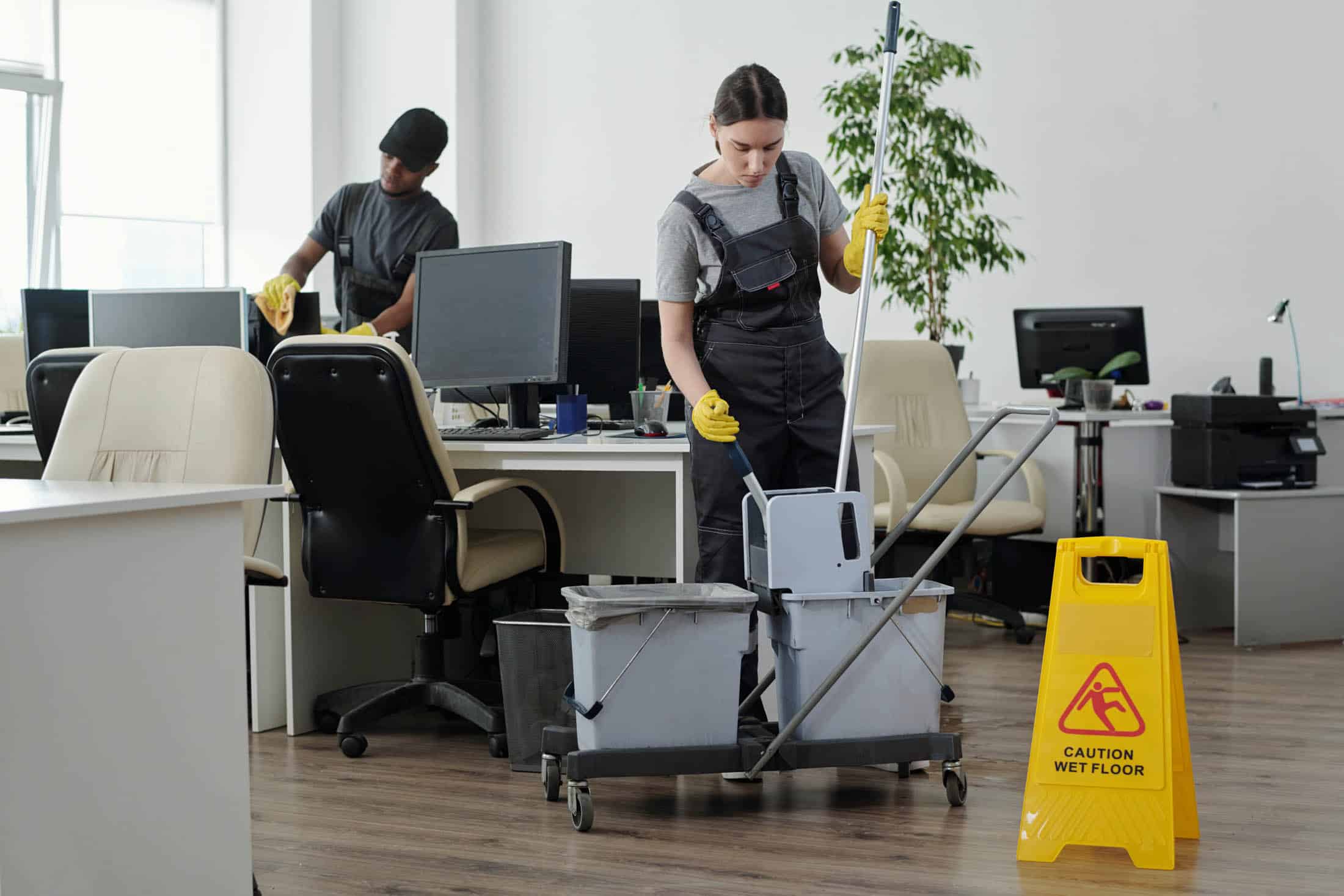 Person squeezing a mop in a bucket with professional janitorial equipment in an office
