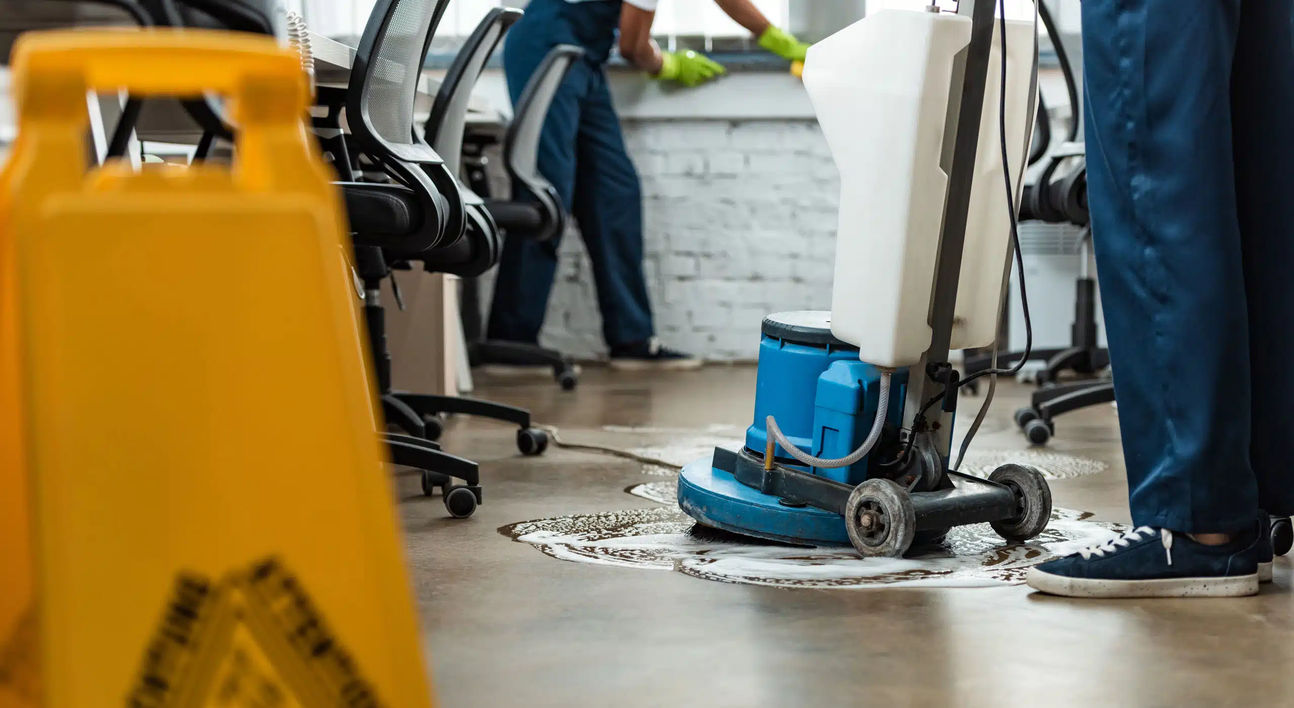 Closeup of a person using a floor cleaning machine on a commercial floor