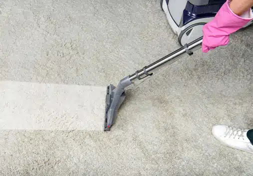 Closeup of a vacuum moving across a white carpet