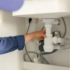 Hand adjusting plumbing under sink