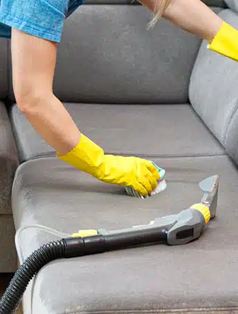 Person cleaning an upholstered sofa